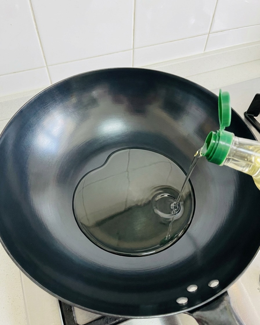 Olio doliva versato in un wok riscaldato.