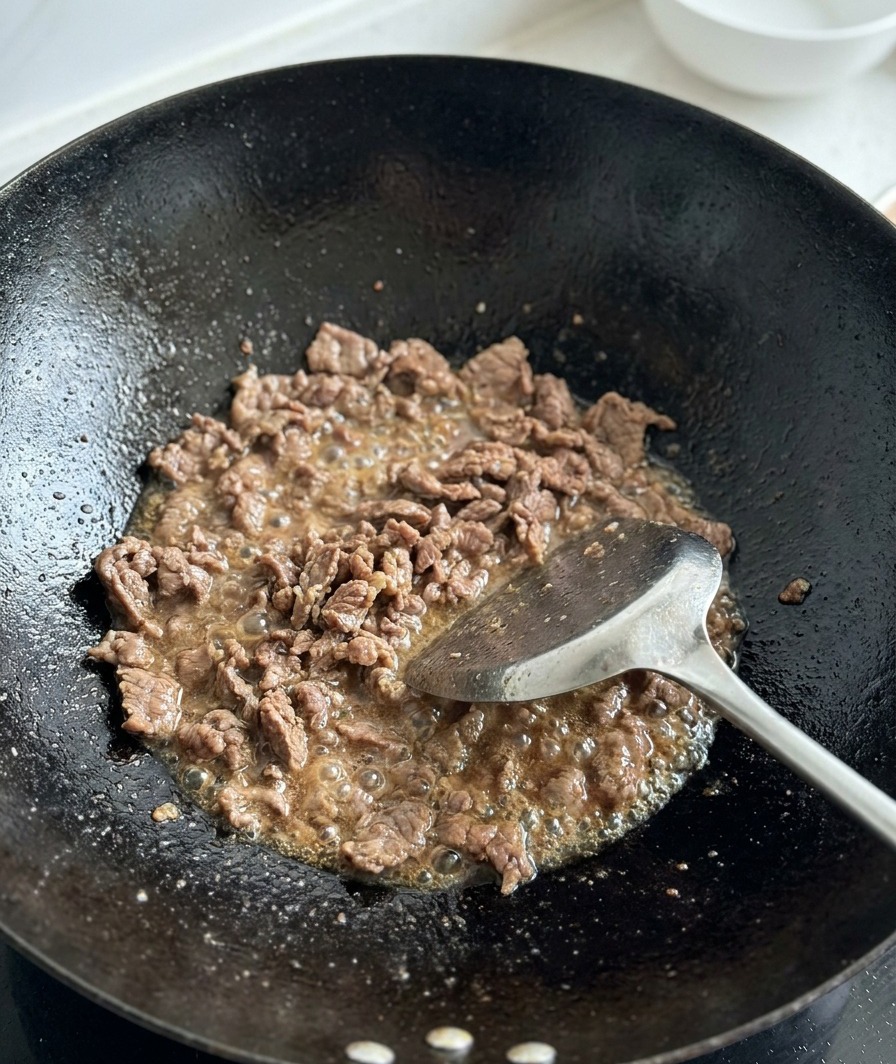 Pomodori freschi a cubetti aggiunti alla carne rosolata.