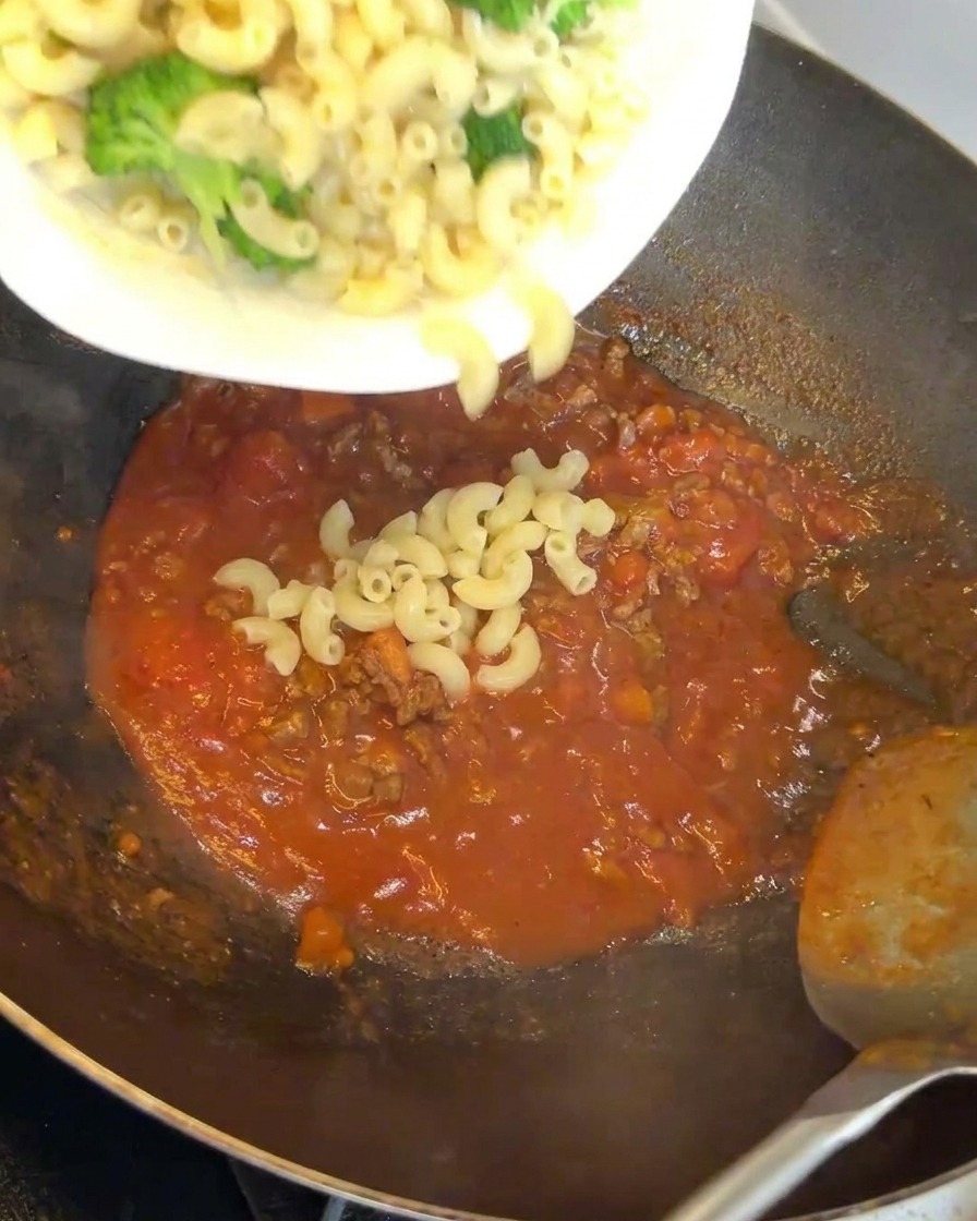Maccheroni e broccoli aggiunti al sugo di carne nel wok.