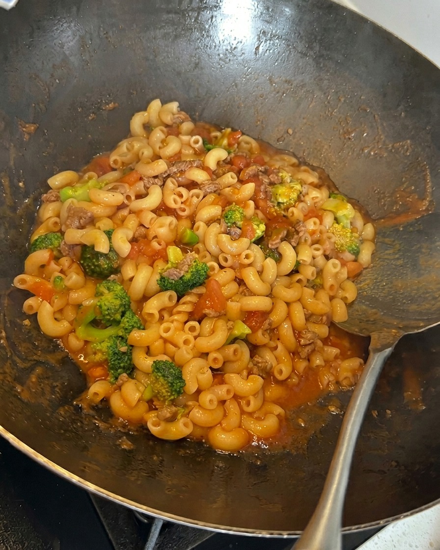 Formaggio grattugiato cosparso sulla pasta nel wok.