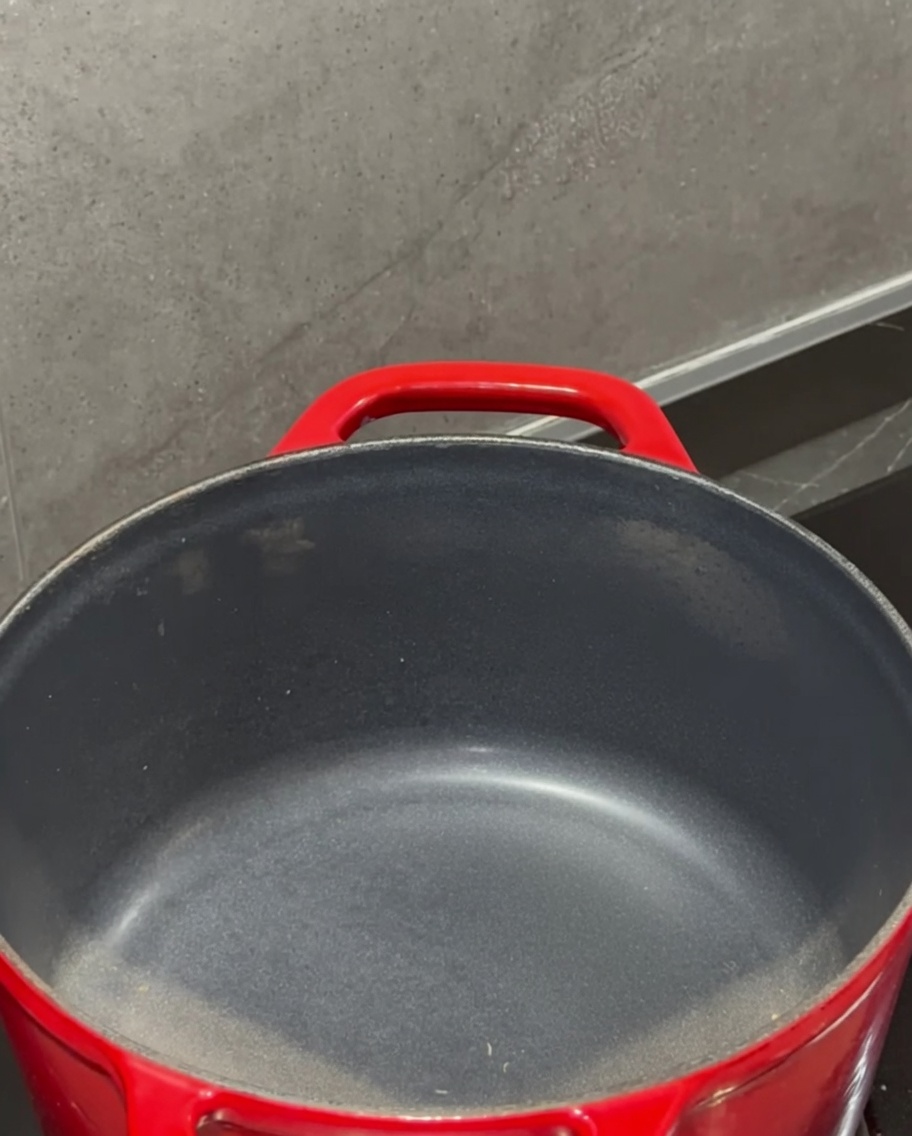 Un panetto di burro che si scioglie in una pentola rossa sul fornello.