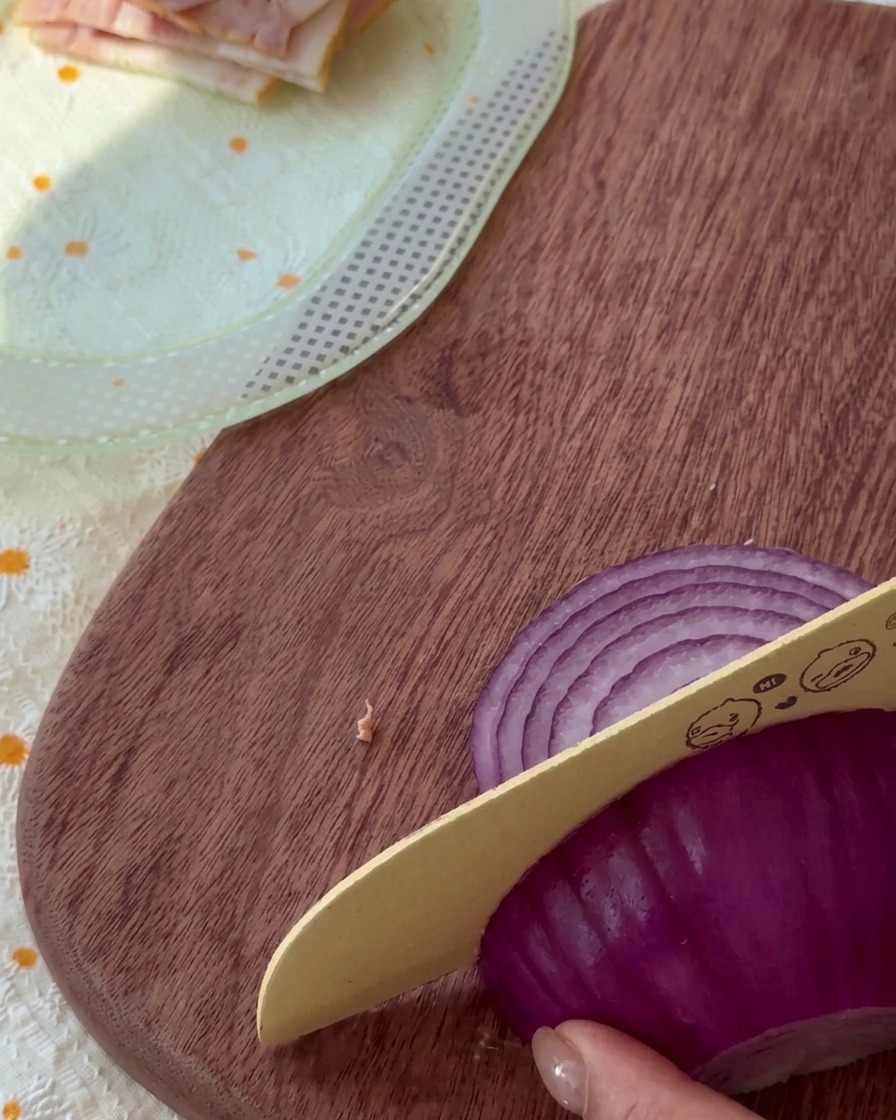 Cipolla rossa cruda tagliata a listarelle sottili su un tagliere di legno.