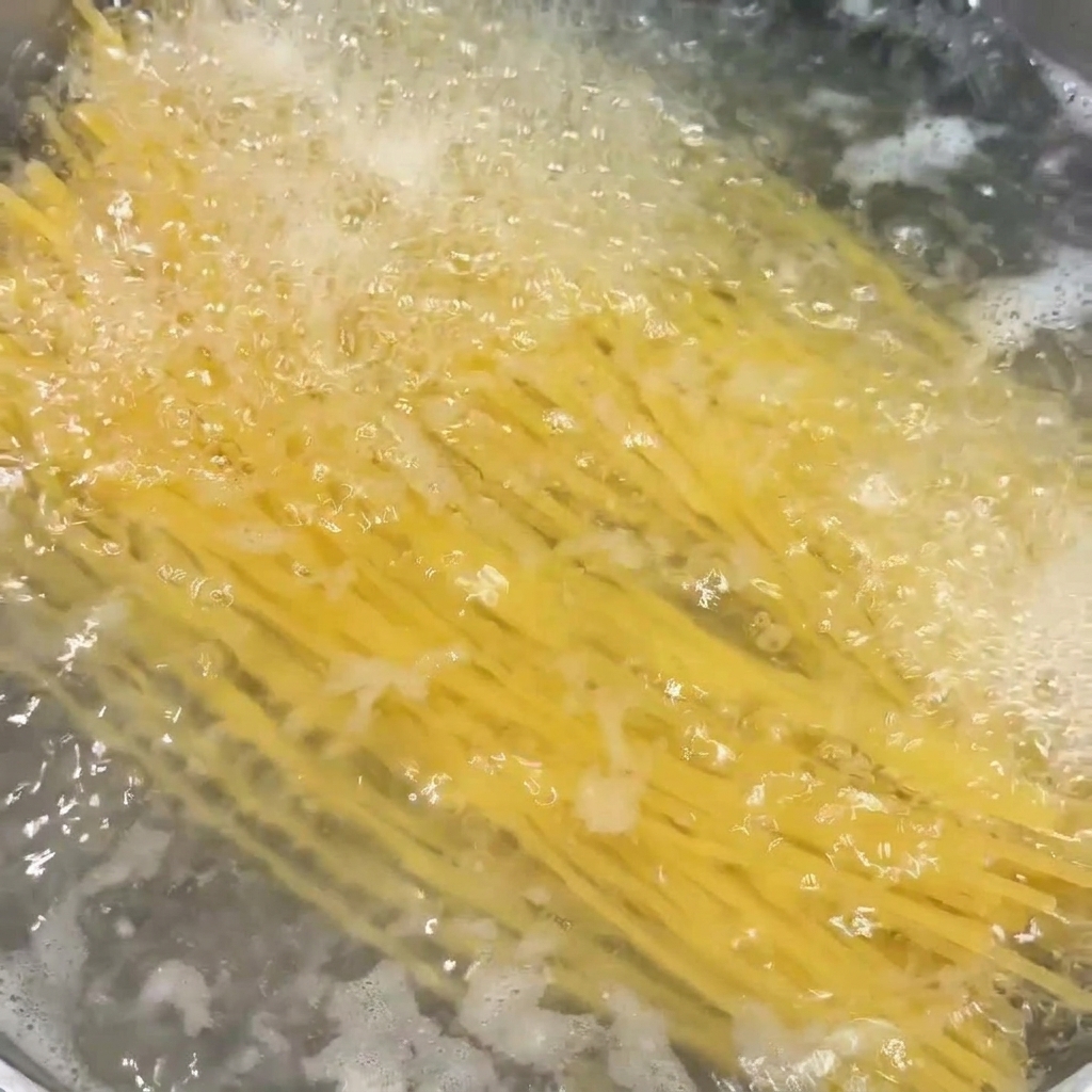 Spaghetti immersi e in cottura in una pentola di acqua che bolle vigorosamente.