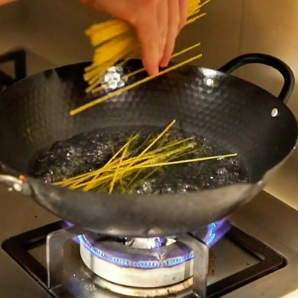 Gli spaghetti di mais immersi in una pentola dacqua bollente.