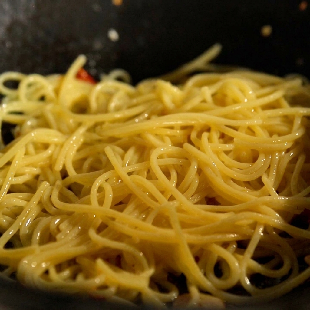 Pasta cotta e un cubetto di burro aggiunti in padella con aglio e peperoncino.