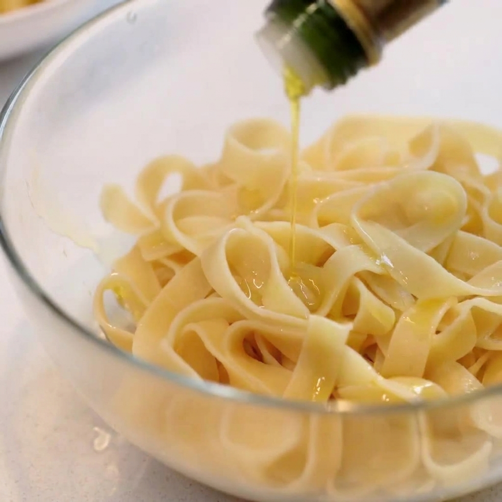 Pappardelle cotte in una ciotola di vetro trasparente condite con olio doliva.