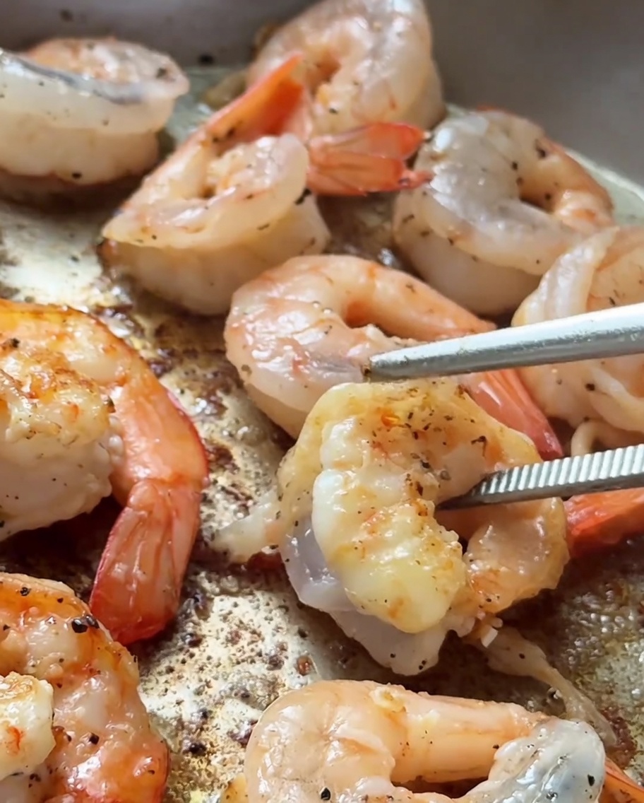 Gamberi in padella calda con una doratura sui bordi.