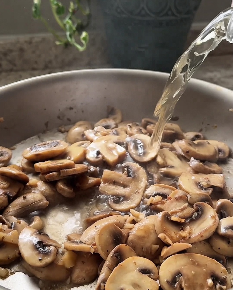 Vino bianco versato in padella sui funghi saltati.