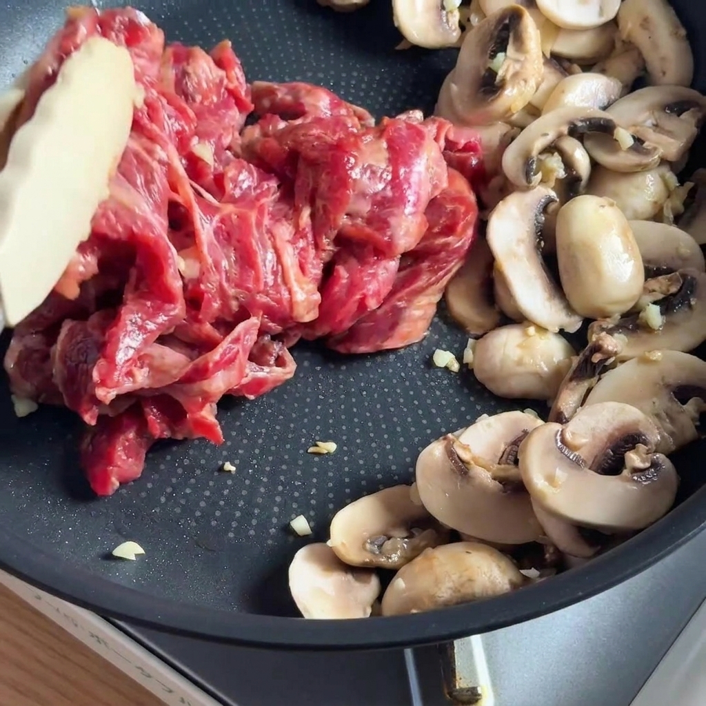Strisce di manzo marinate che saltano in padella insieme ai funghi affettati.