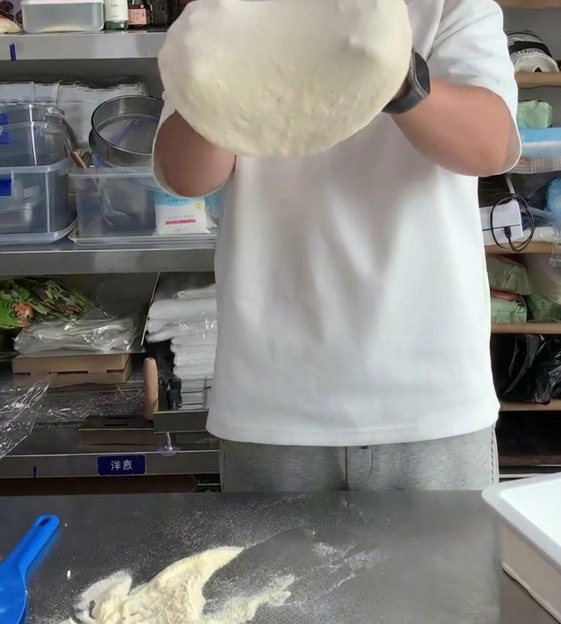 Impasto per pizza teso sulle nocche per aumentarne il diametro e assottigliare il centro.