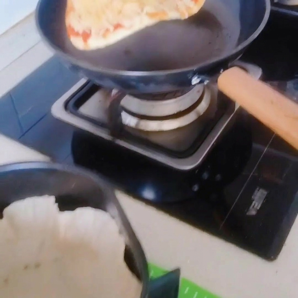 La pizza trasferita con attenzione dalla padella al cestello della friggitrice ad aria rivestito di carta forno.