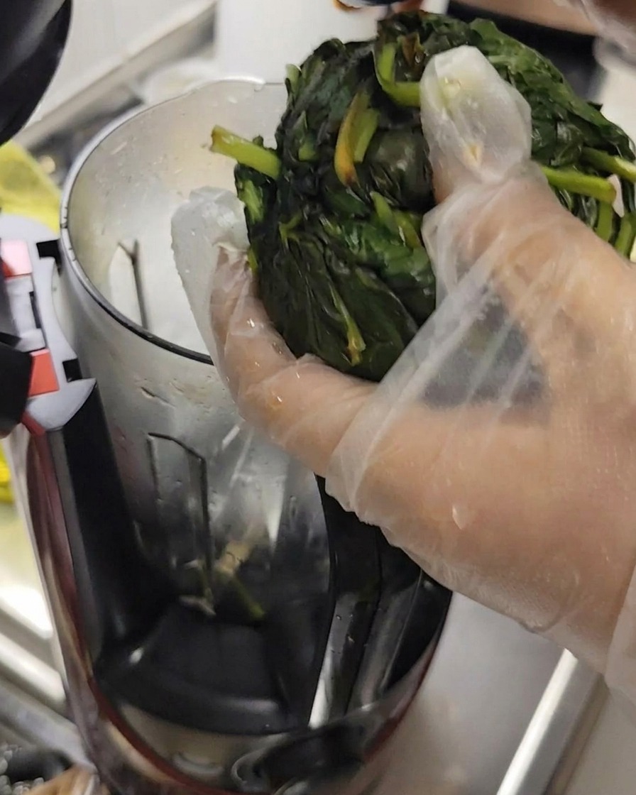 Foglie di basilico strizzate dallacqua con guanti, pronte per il robot da cucina.