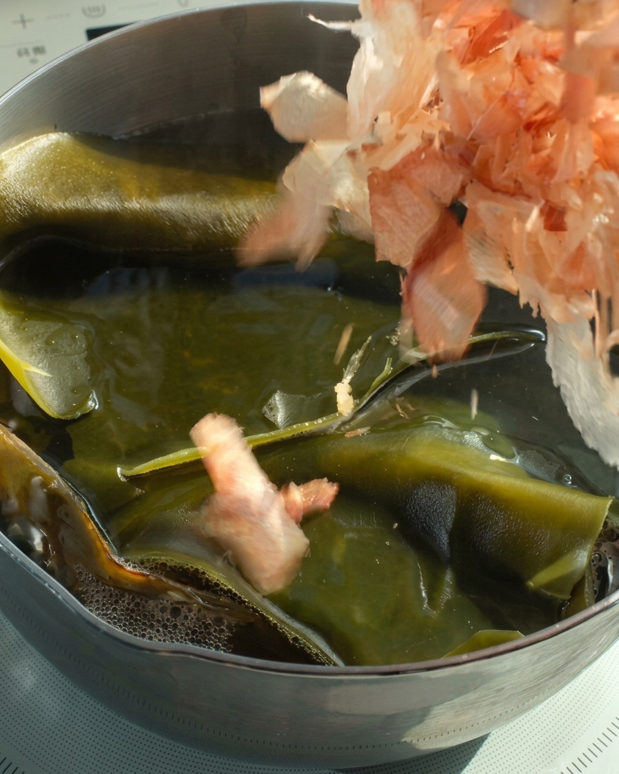 Fiocchi di bonito versati in un pentolino di brodo caldo di kombu.