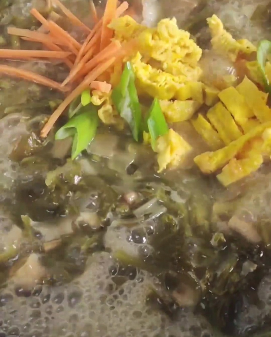 Carote e uova fritte a strisce aggiunte in una pentola bollente di brodo con senape.