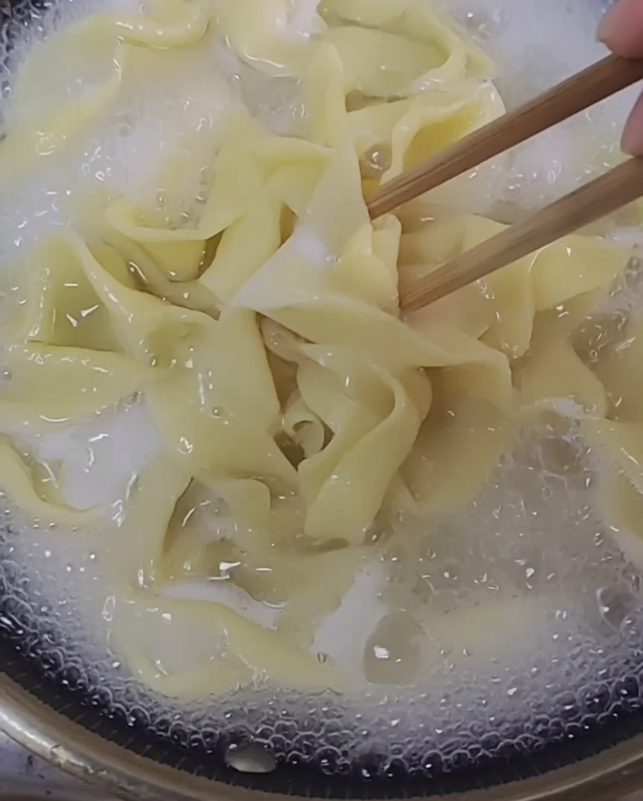 Fili di pasta fresca che bollono in una pentola dacqua limpida.