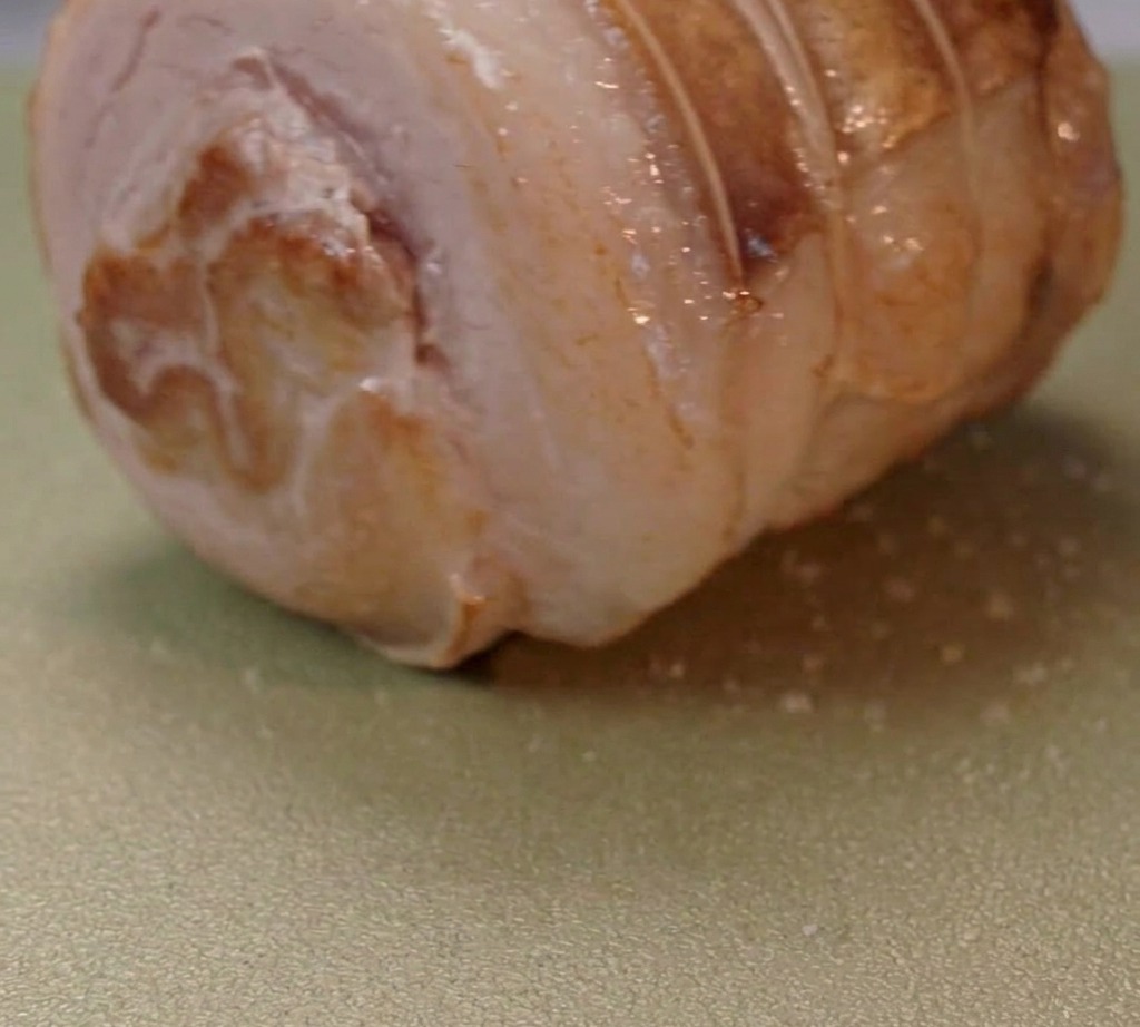 Pancetta arrotolata che rosola in una padella con olio.