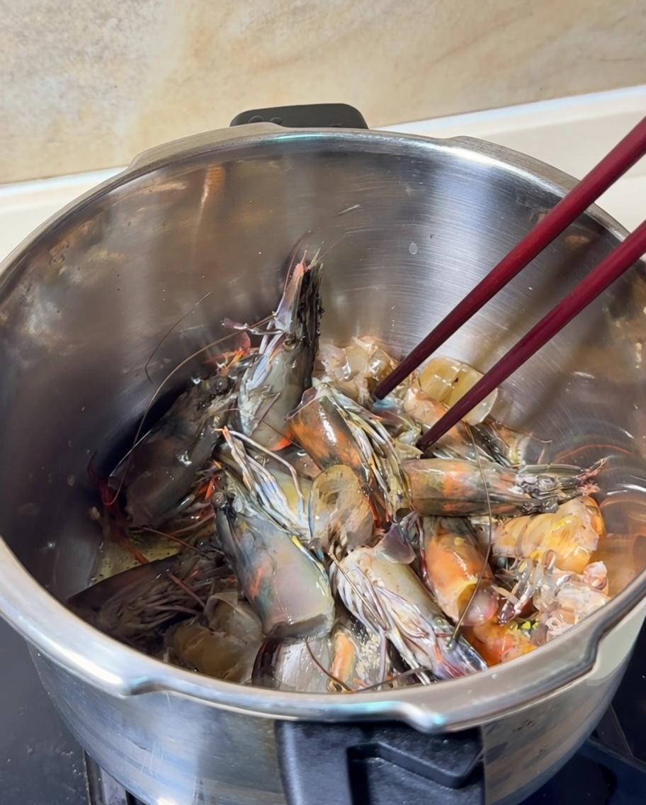 Teste e carapaci di gambero saltati in una pentola, assumendo un colore arancione brillante.