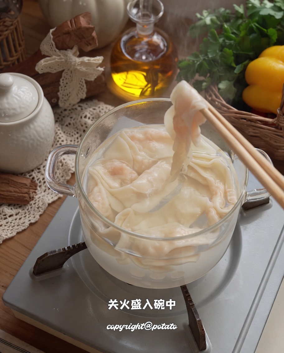 Noodles di gamberi cotti sollevati dalla pentola con le bacchette verso la ciotola.