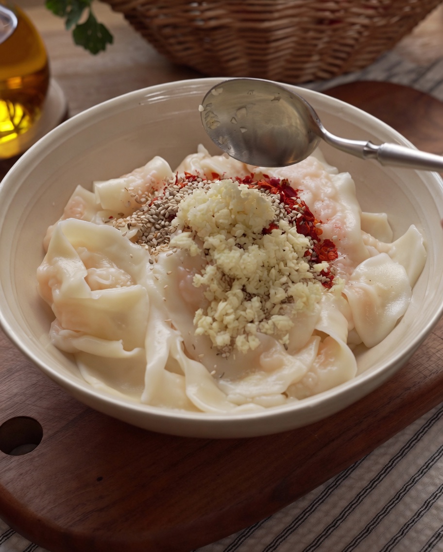 Olio bollente versato da un mestolo sopra le spezie e laglio nella ciotola.