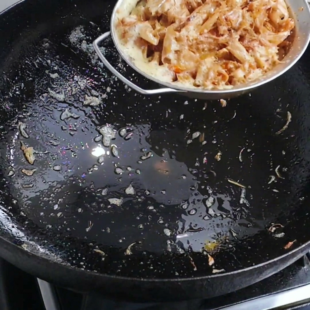 Acqua calda versata in un wok contenente gusci di gambero per creare un brodo saporito.