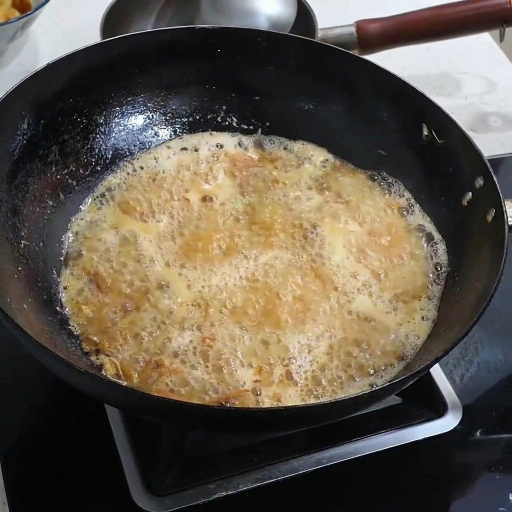 Sale che viene cosparso in un brodo di gamberi dorato e bollente.