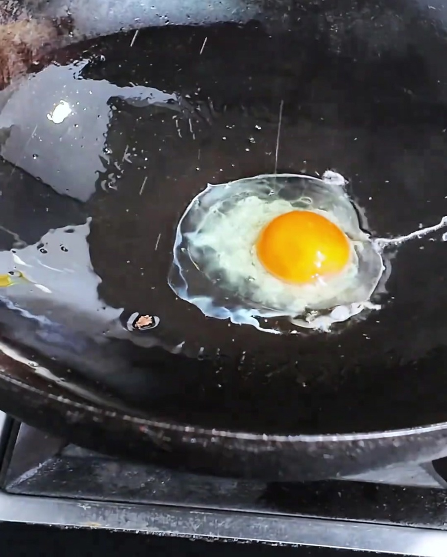 Un uovo che frigge in un wok caldo.