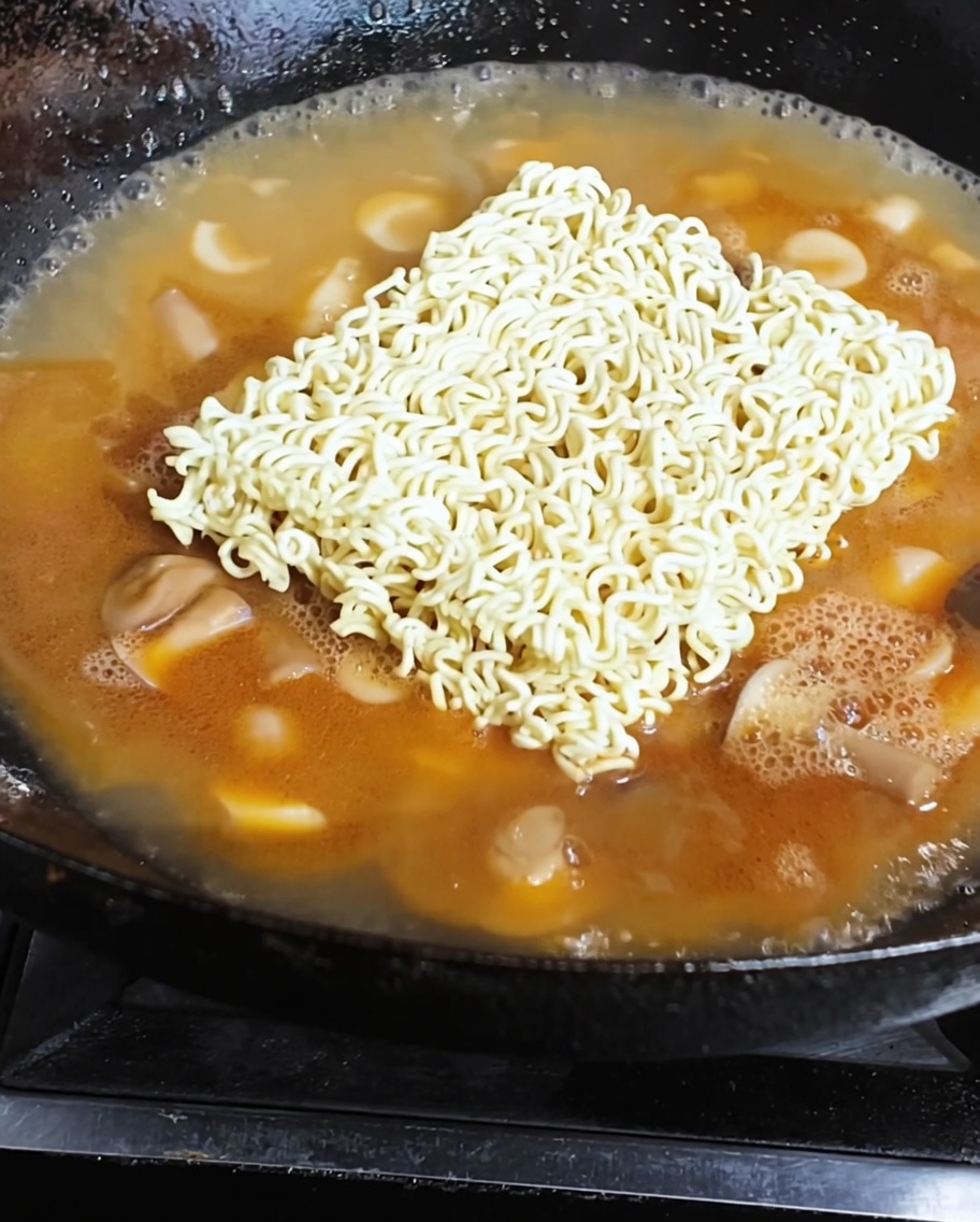 Noodles istantanei e un uovo fritto che cuociono in un brodo ricco e saporito.