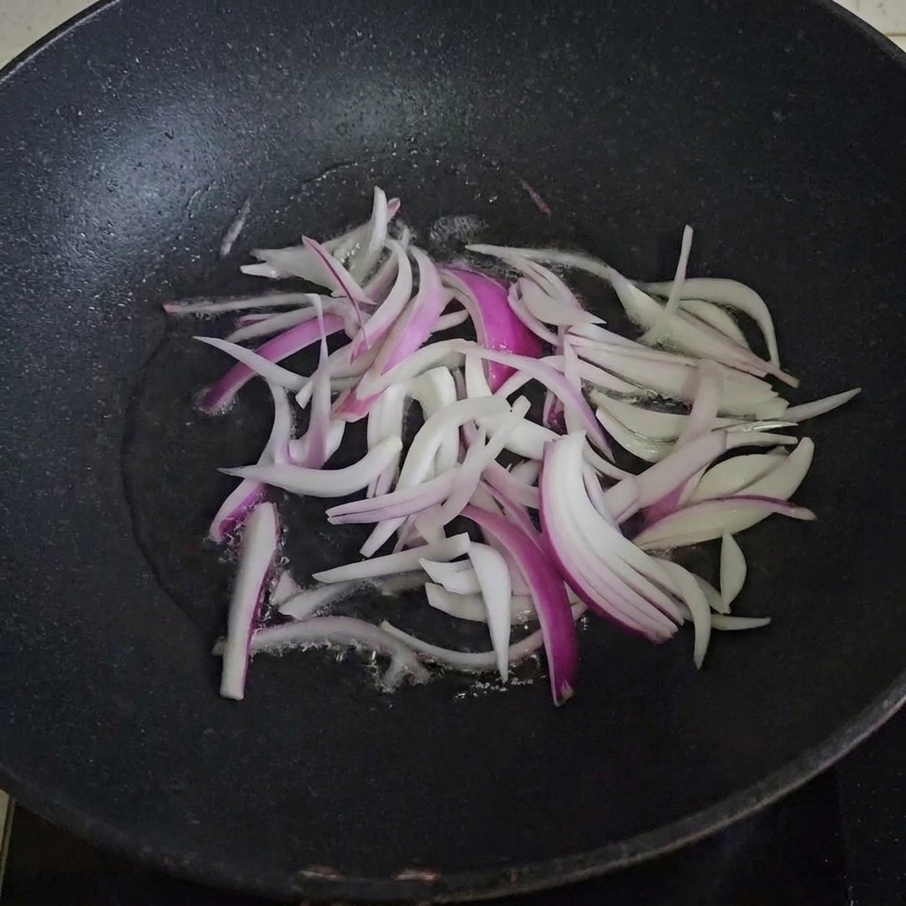 Fette di cipolla che cuociono in una padella calda oleata.