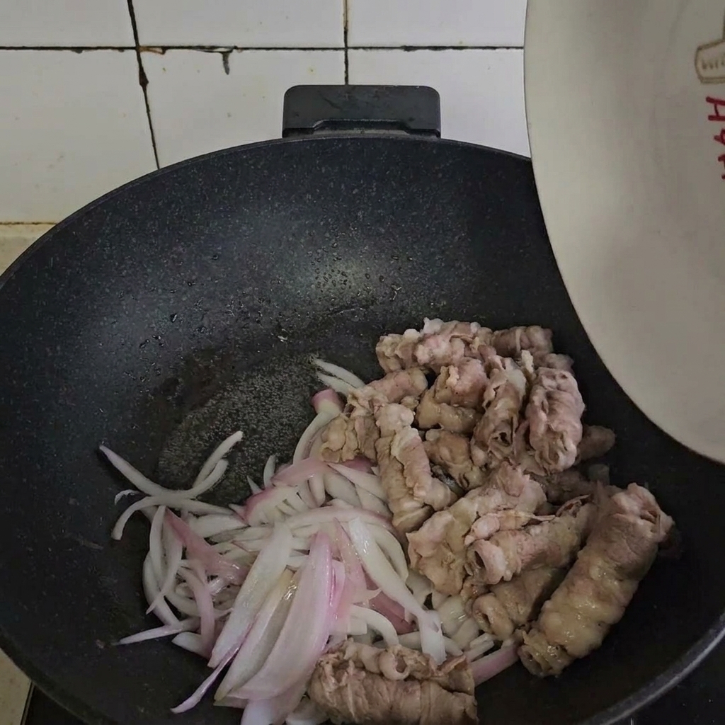 Il manzo sbollentato viene unito alle cipolle saltate in padella.