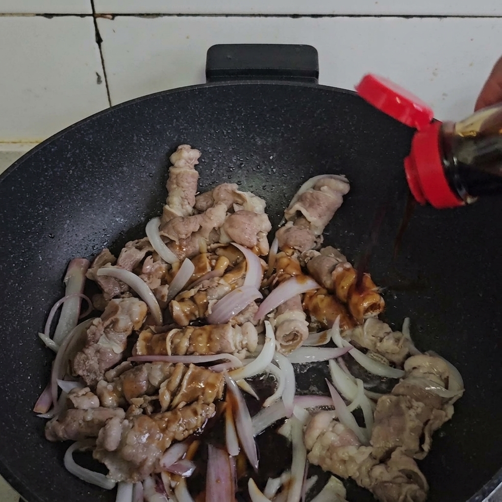 Manzo e cipolle mescolati con la salsa in una padella calda.