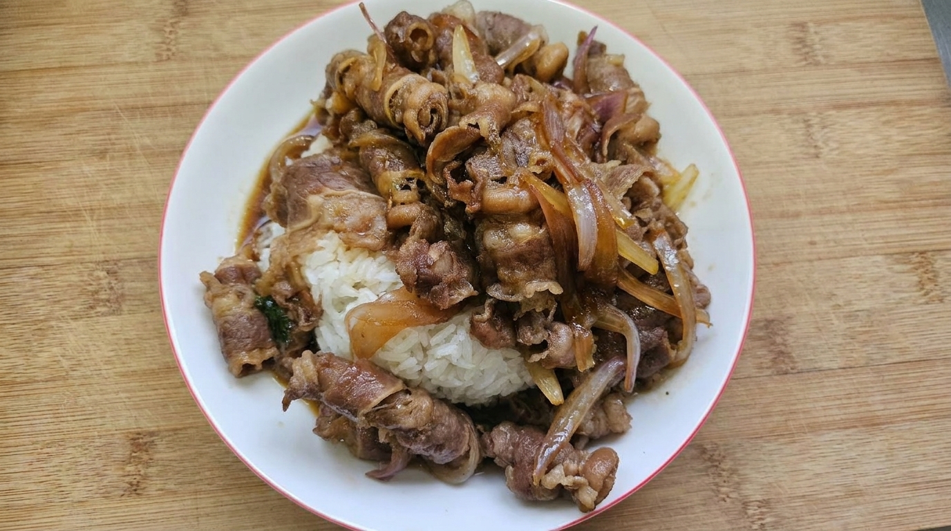 Una classica ciotola di Gyudon, con manzo tenero glassato e fette di cipolla disposte su una base di riso bianco.