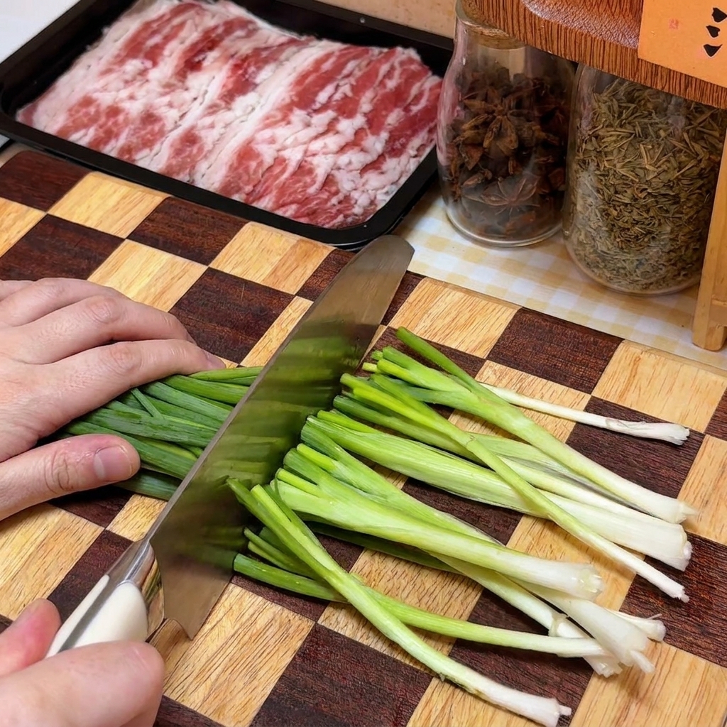 Cipollotti tritati finemente su un tagliere in legno a scacchi vicino a un contenitore di carne.