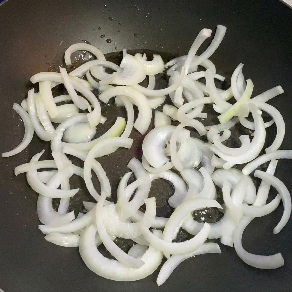Fette di cipolla che soffriggono in una padella con olio caldo.