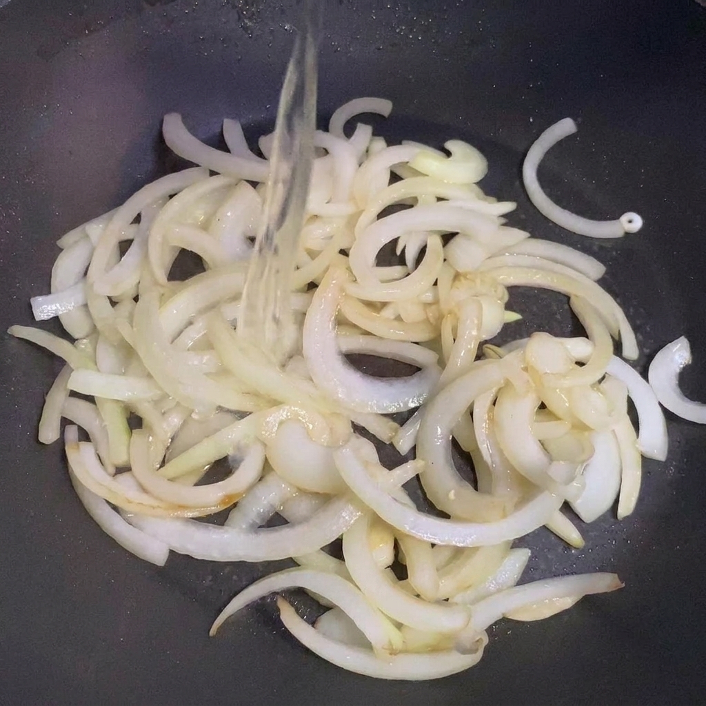 Sake versato sulle cipolle che saltano in padella.