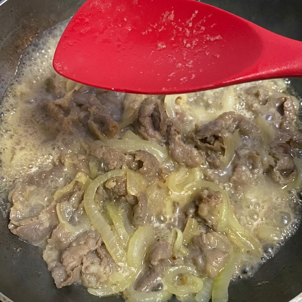 Salsa di soia aggiunta al composto di manzo e cipolla in ebollizione.