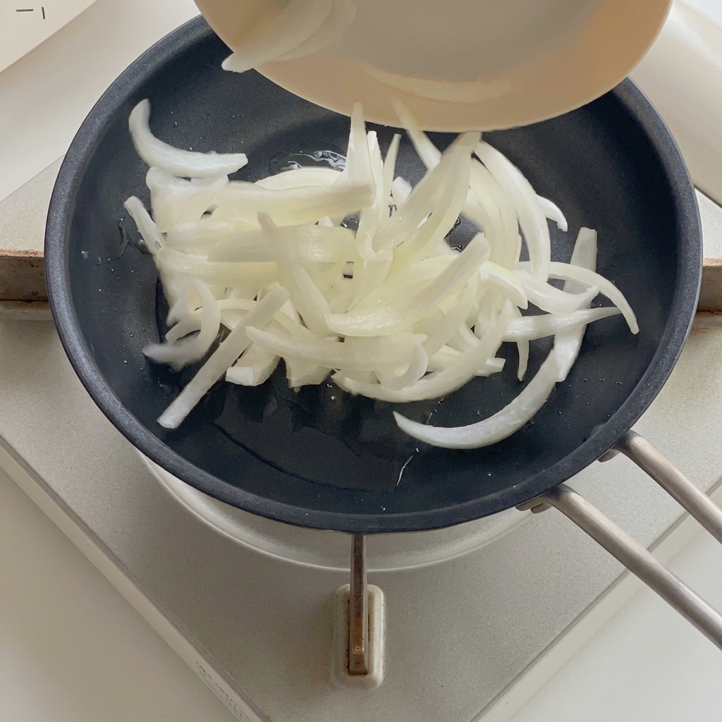 Cipolle che si ammorbidiscono in una padella con olio caldo.