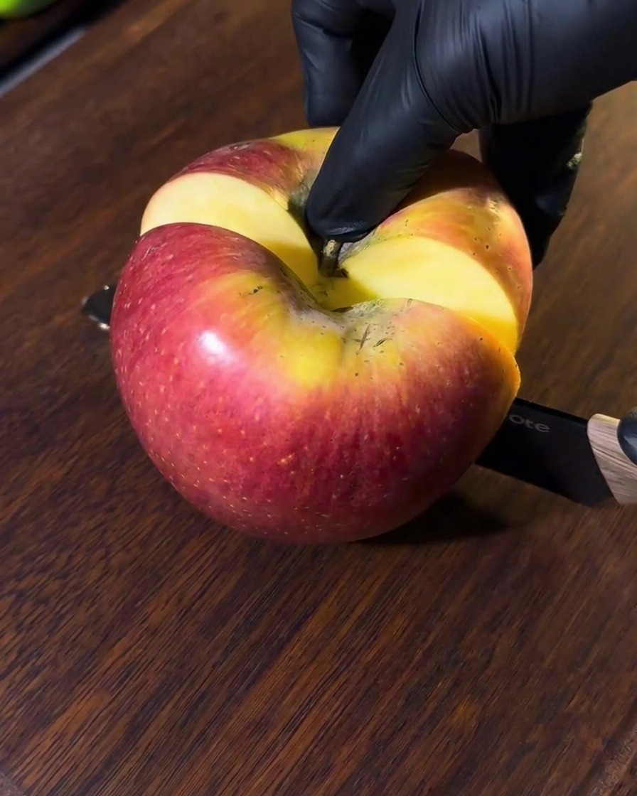 Una mela tagliata su un tagliere di legno, pronta per essere frullata.