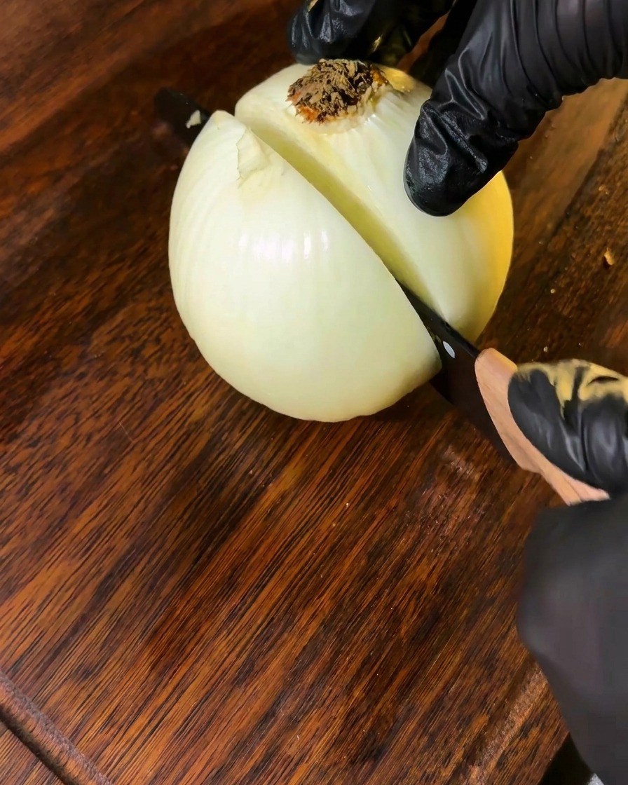Una cipolla affettata su un tagliere di legno, pronta alluso.