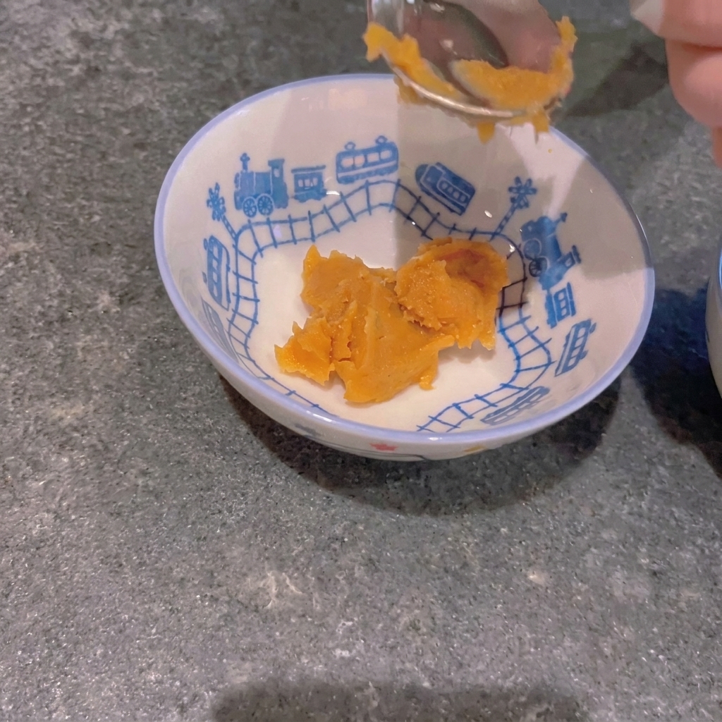 Un cucchiaio di pasta di miso gialla posta in una piccola ciotola con decorazioni a forma di treno.