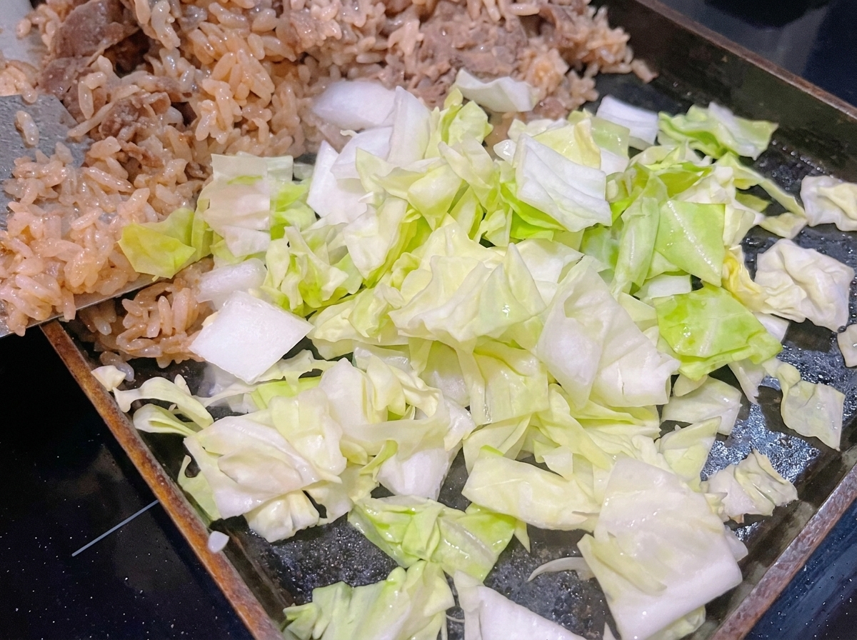 Cavolo verde fresco appena tritato posizionato sopra il riso bianco e il manzo in una padella calda.
