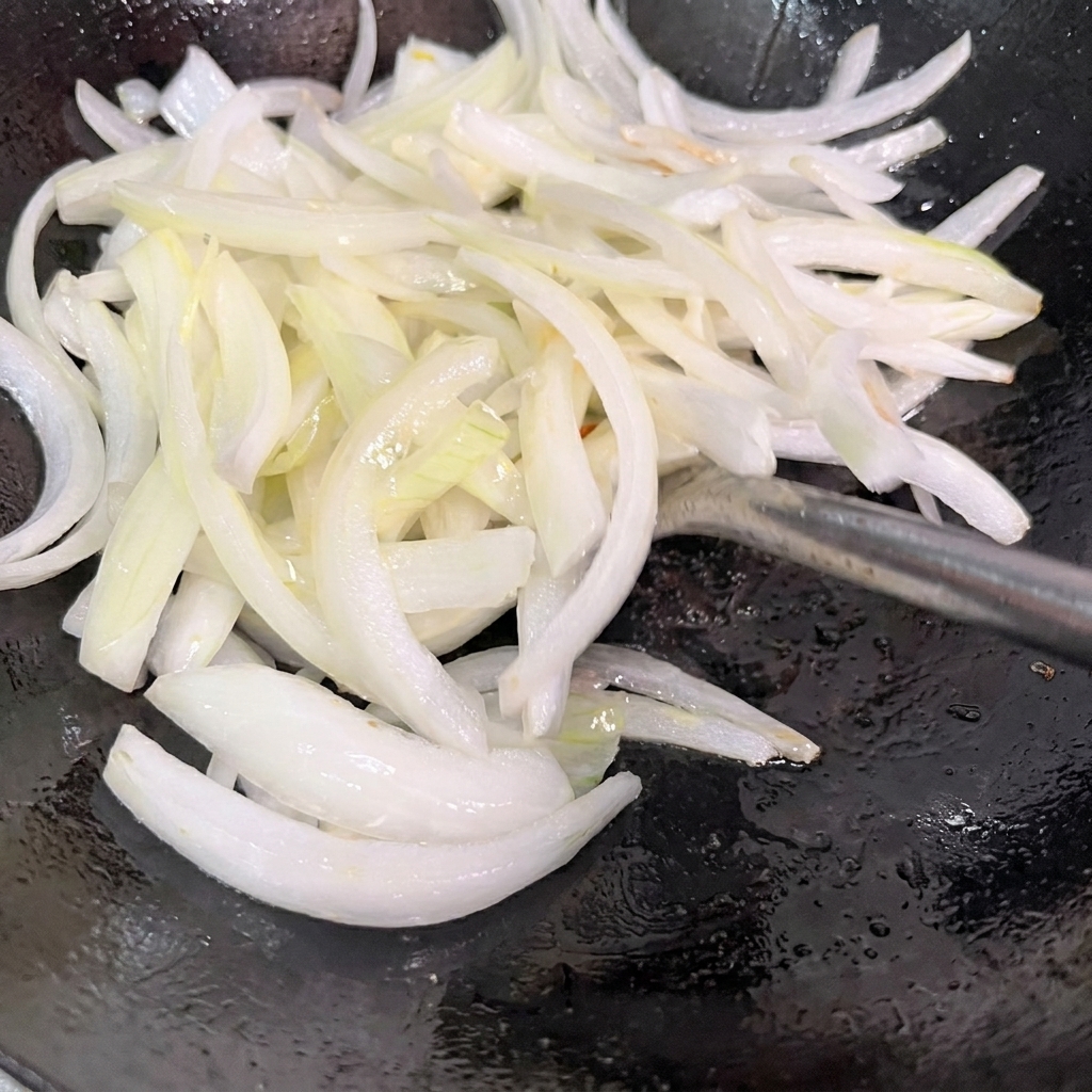 Cipolle affettate saltate in un wok caldo.