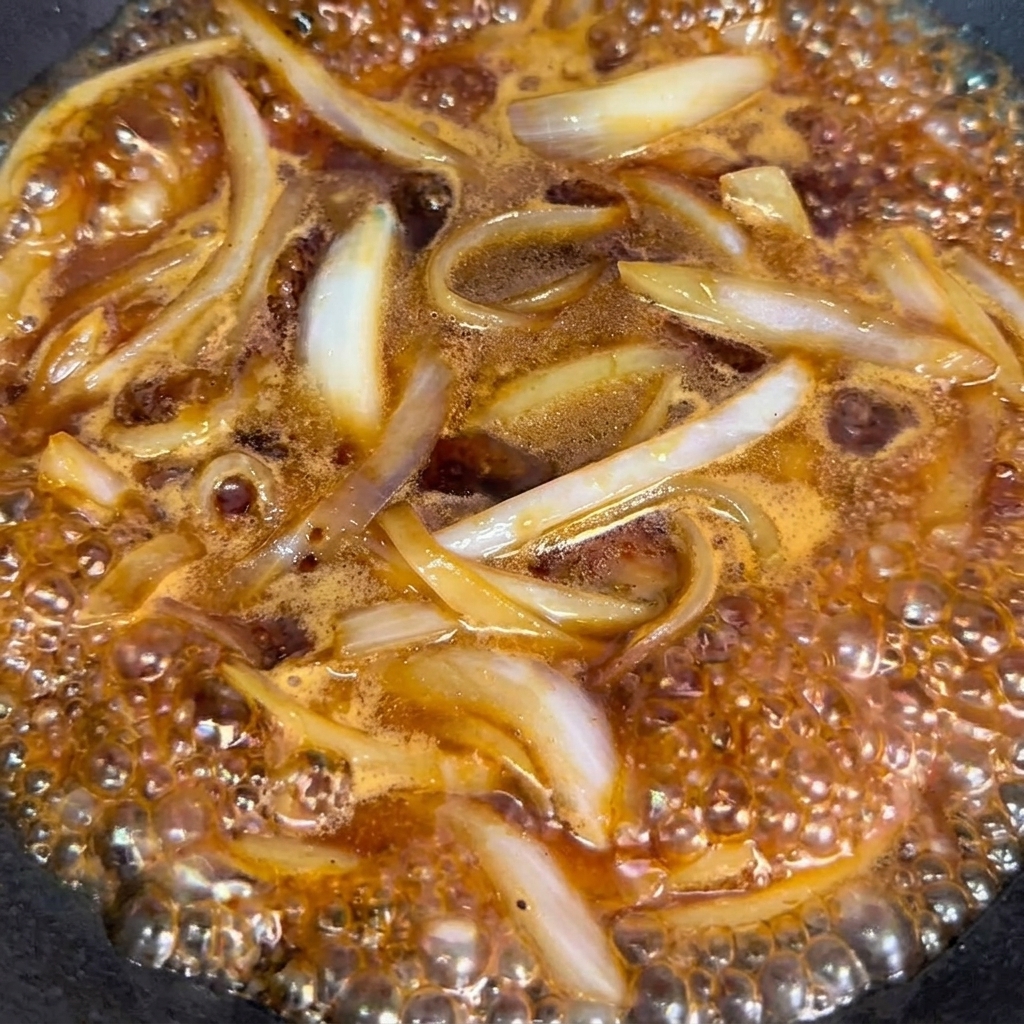 Manzo sbollentato aggiunto nel wok con cipolle e salsa.