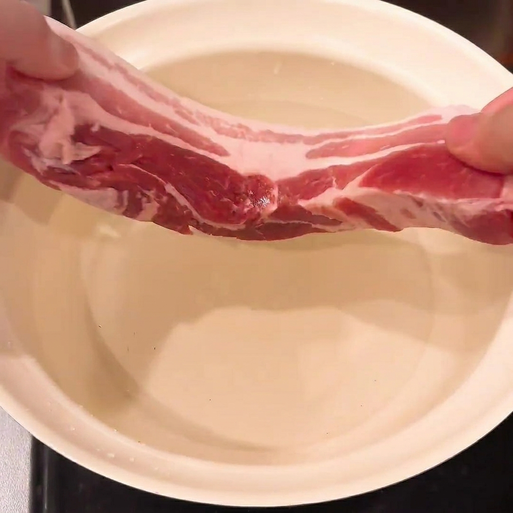 Pancetta, cipollotto e zenzero in una pentola dacqua pronti per la bollitura.