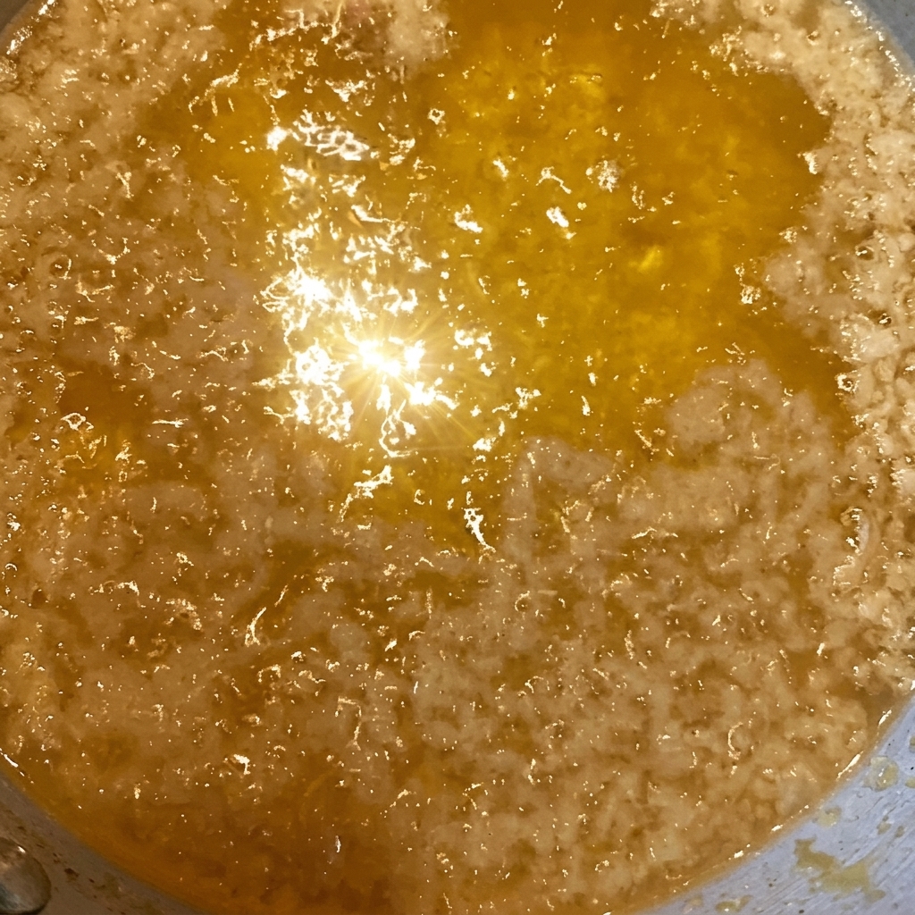 Primo piano di frammenti di tempura dorati e croccanti sparsi su una ciotola di riso già lucida di una salsa scura a base di soia.