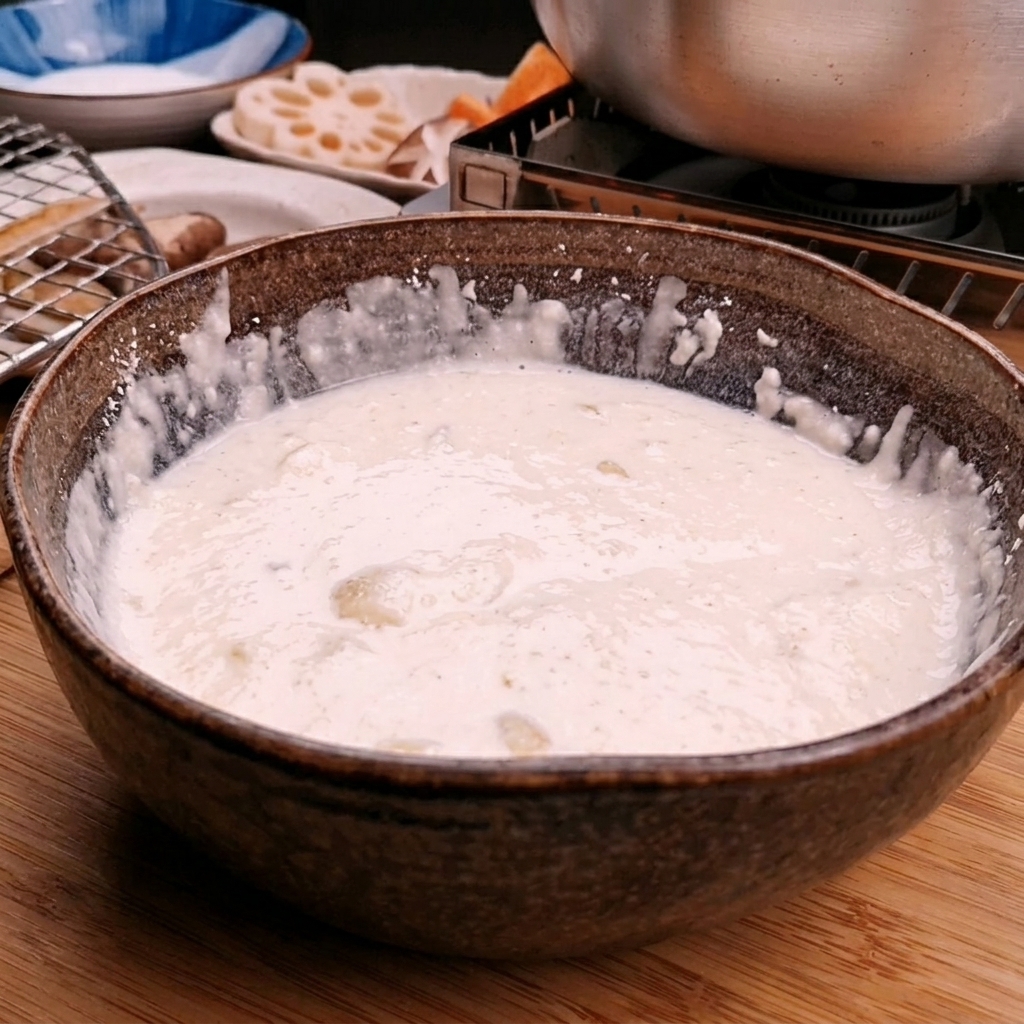 Acqua ghiacciata versata in una ciotola di farina per tempura per creare una pastella liscia.