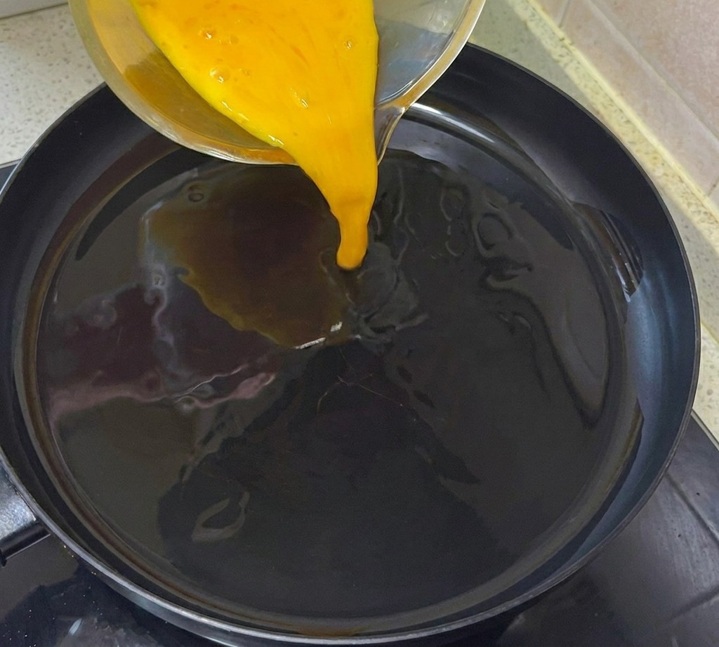 Il composto di uova sbattute versato in una padella preriscaldata e oliata.