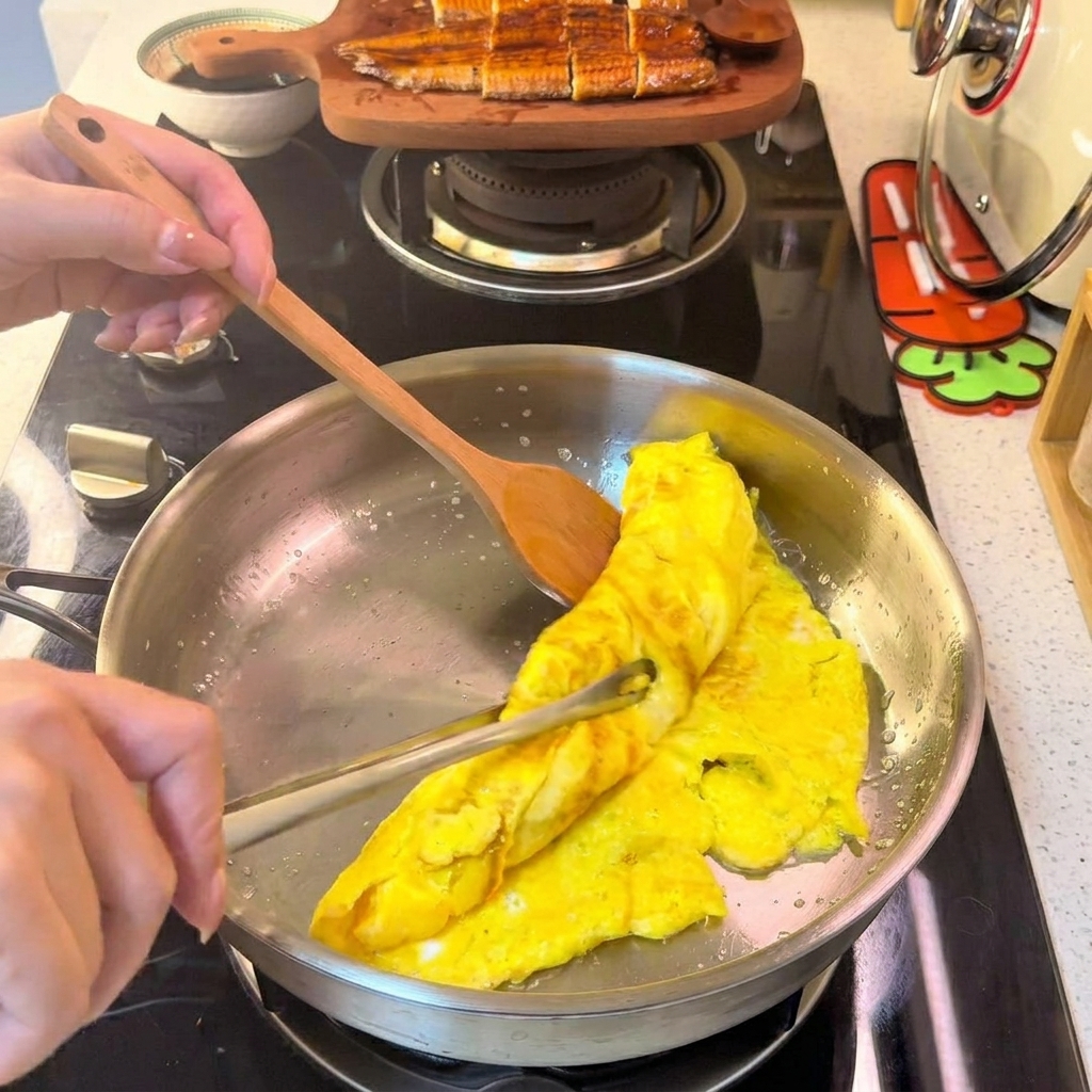 Una frittata arrotolata che viene tagliata in strisce sottili e uniformi su un piatto bianco.