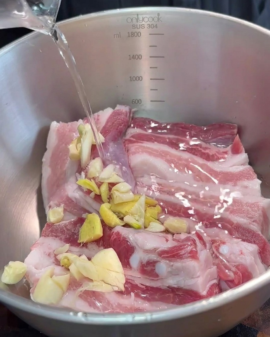 Una ciotola con le strisce di maiale condite con aromi tritati e salsa di tofu fermentato rosso.