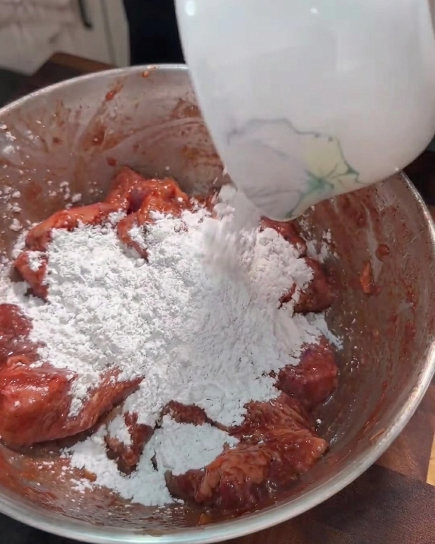 Fecola di patate dolci versata nella ciotola con le strisce di pancetta marinate.