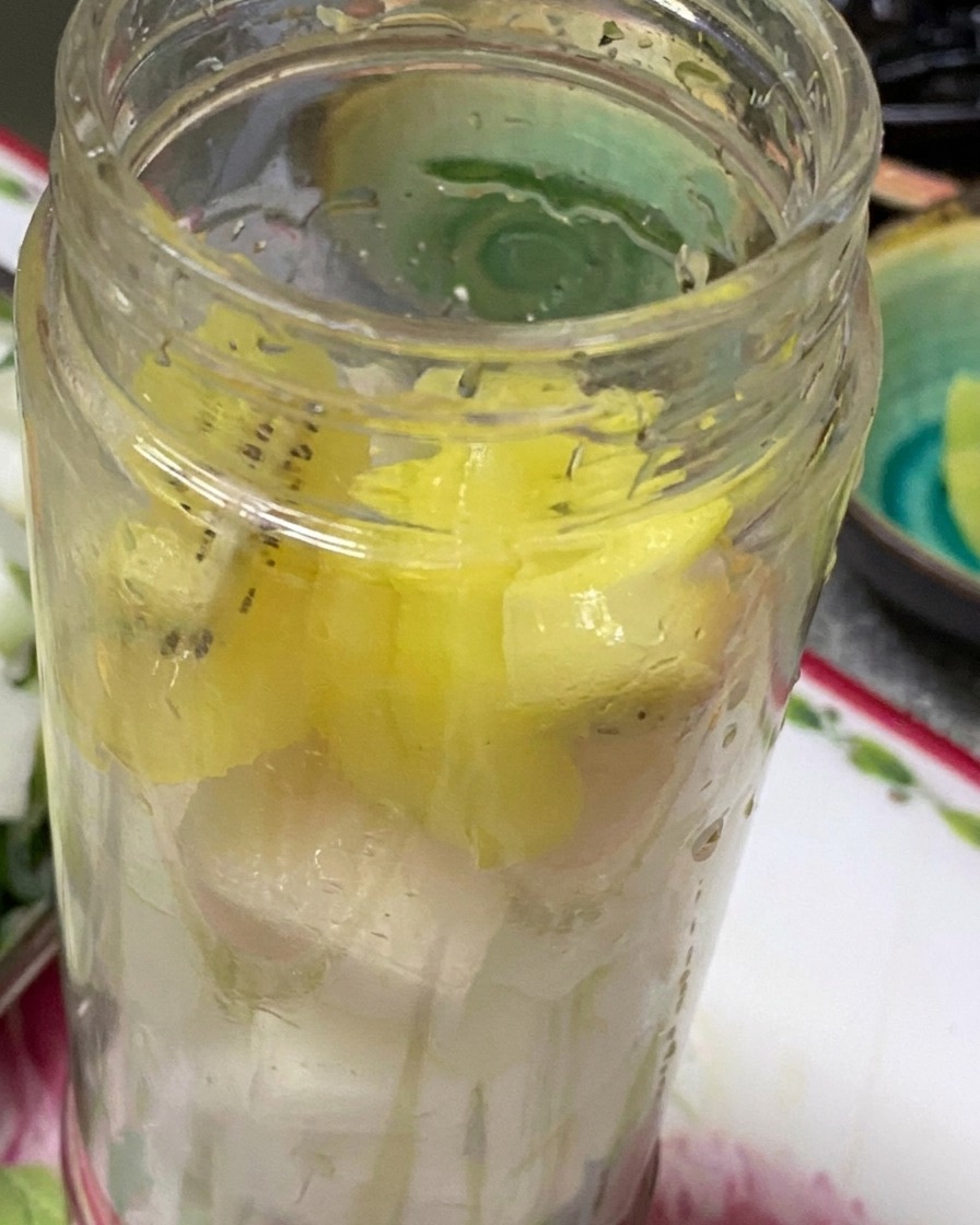 Pezzi di cipolla, aglio, kiwi e pera allinterno della caraffa di un frullatore pronti per essere frullati.